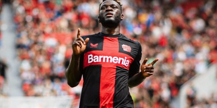 Victor Boniface in Bayer Leverkusen's home red and black jersey celebrating his goal for the club